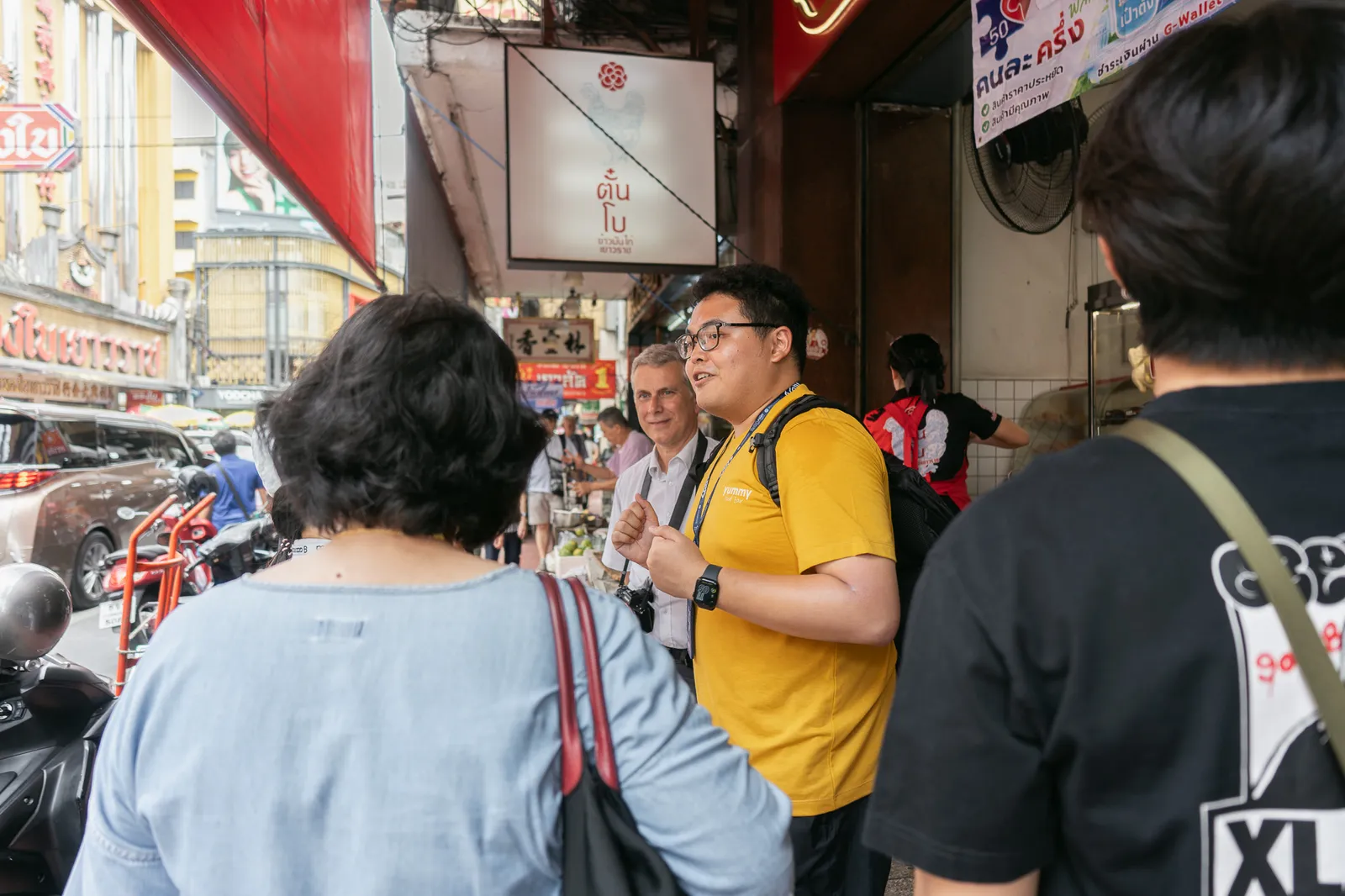 A Yummy guide talking to explorers outside the Tan Bo chicken rice shop on Yaowarat